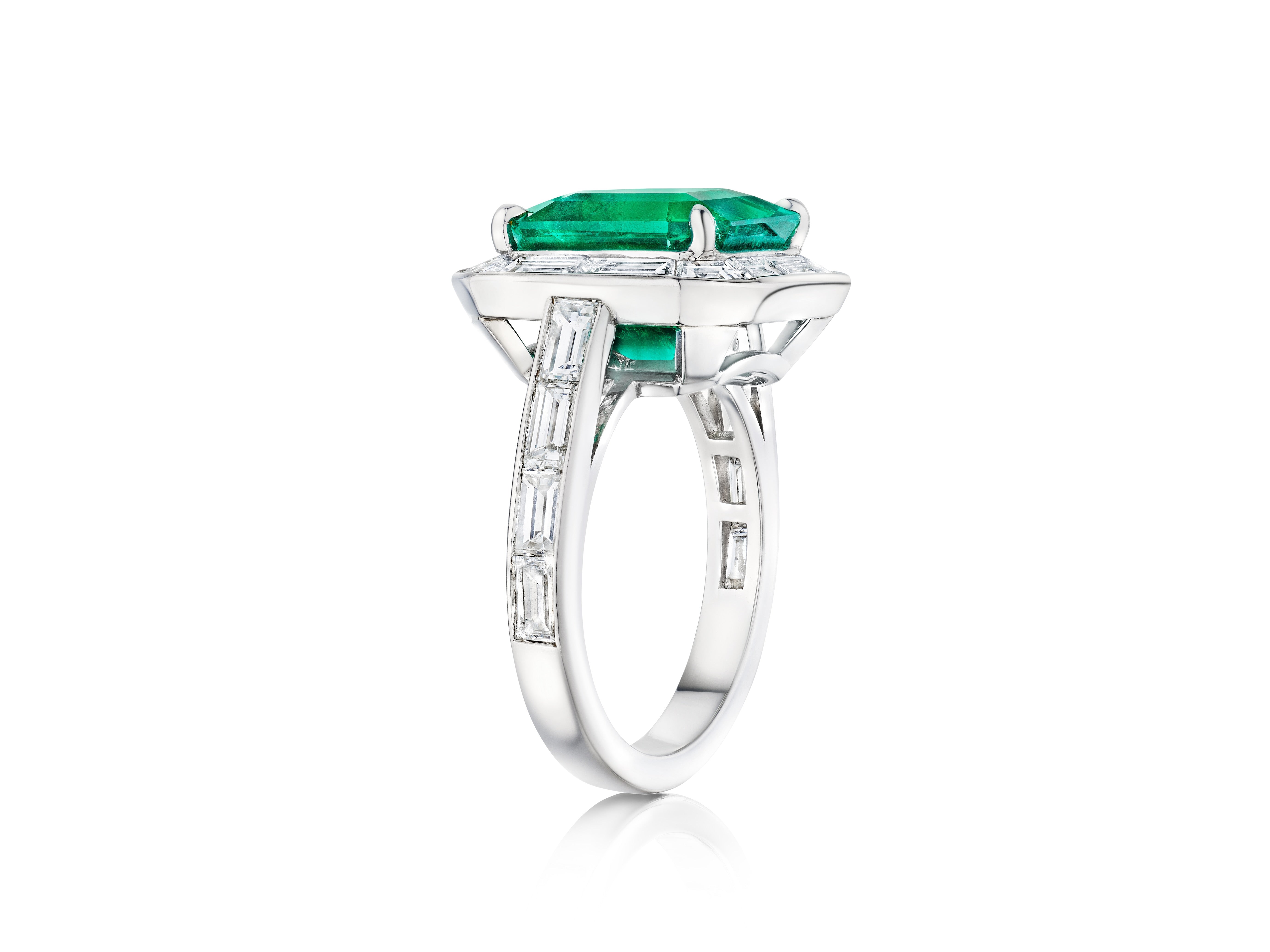 The Mosaic Asscher Cut Emerald and Baguette Diamond Cocktail Ring in Platinum features a striking asscher cut emerald centerpiece with baguette diamond accents, beautifully displayed against a white background.