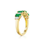The Chroma Alternating Emerald and Diamond Half Eternity Band showcases rectangular green emeralds and emerald-cut diamonds set in 18K gold, arranged in a row along the band and displayed on a white background.