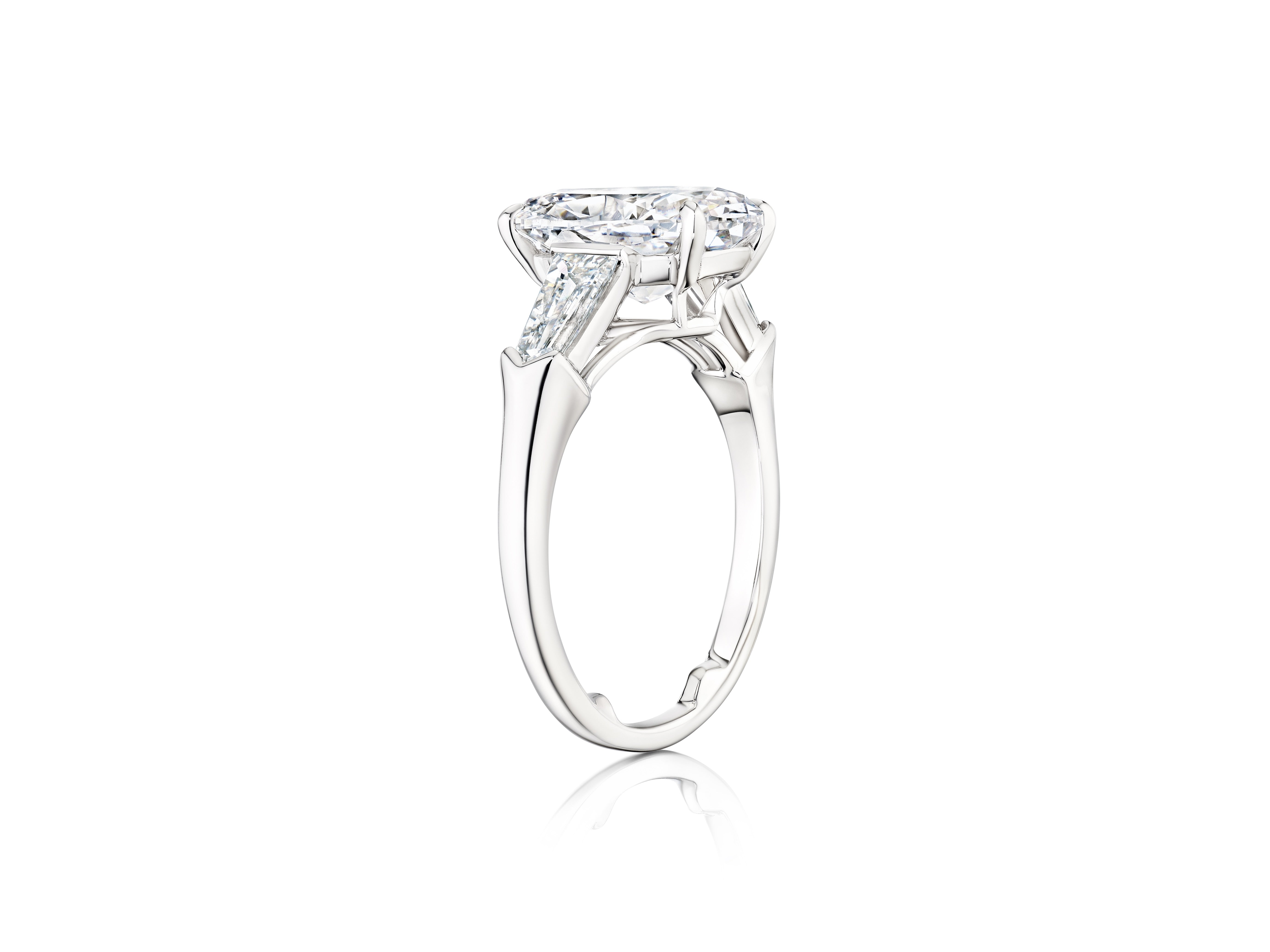 Side view of the Oval Shape Diamond Engagement Ring with Tapered Baguette Side Stones, featuring a large oval diamond center and modern platinum setting, displayed on a plain white background.