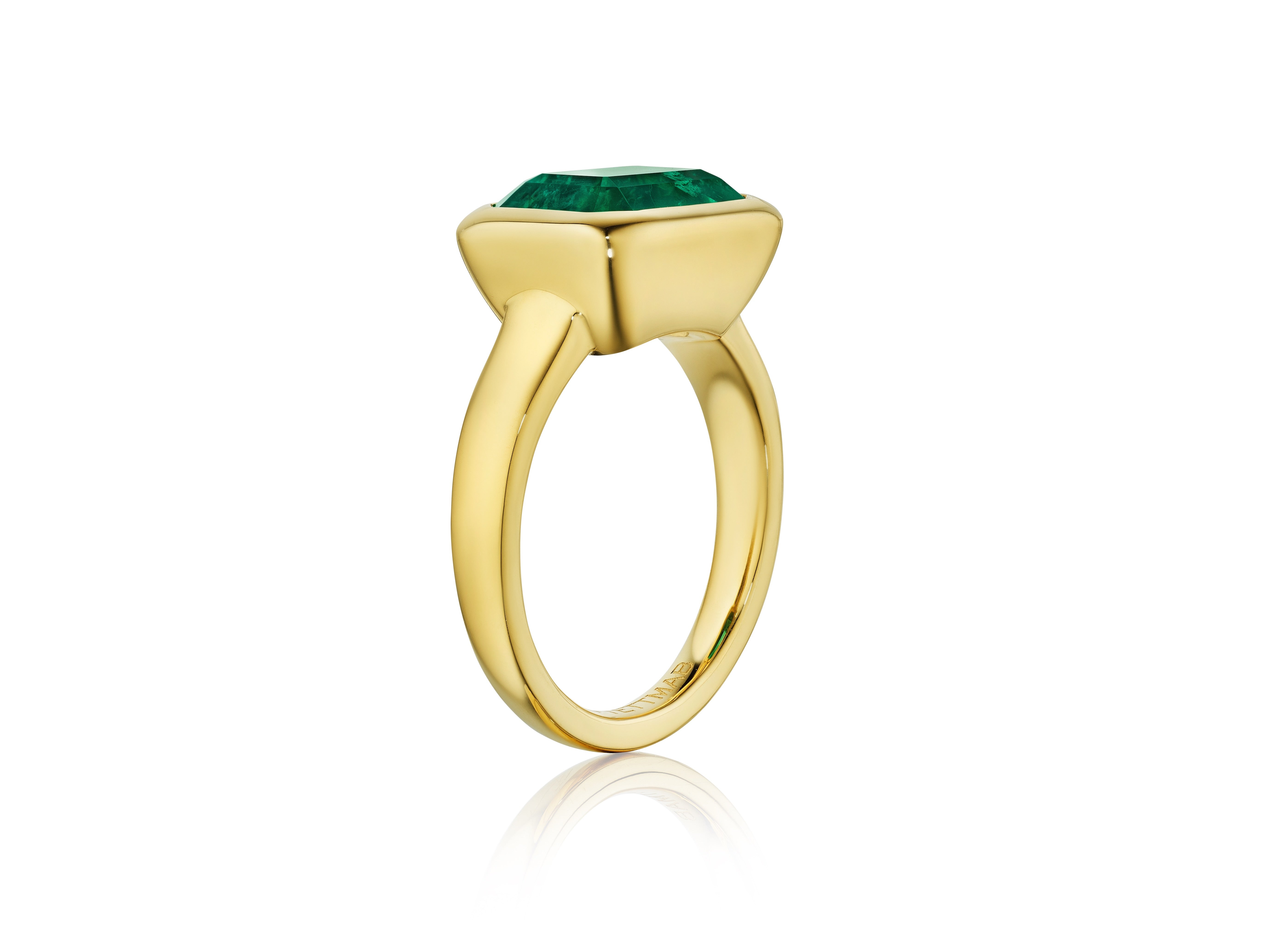 The East-West Bezel Set Emerald Cut Emerald Engagement Ring in Yellow Gold features a striking emerald cut emerald in a modern, minimalist bezel setting, shown on a white background.