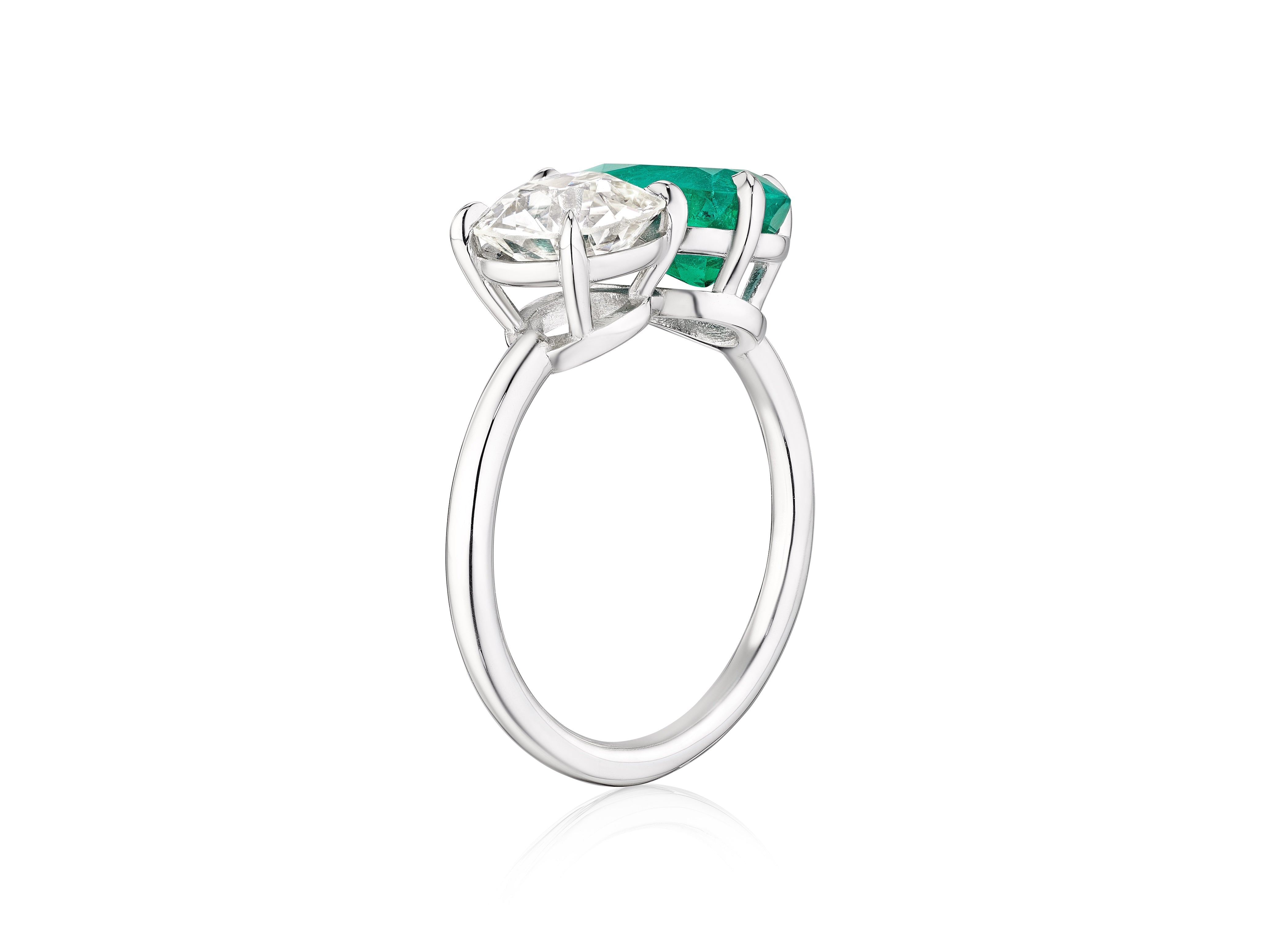 The Bespoke Toi et Moi Pear Shape Emerald and Round Diamond Engagement Ring in White Gold features a pear shape emerald and a round diamond in prong settings, shown from a side angle on a white background.