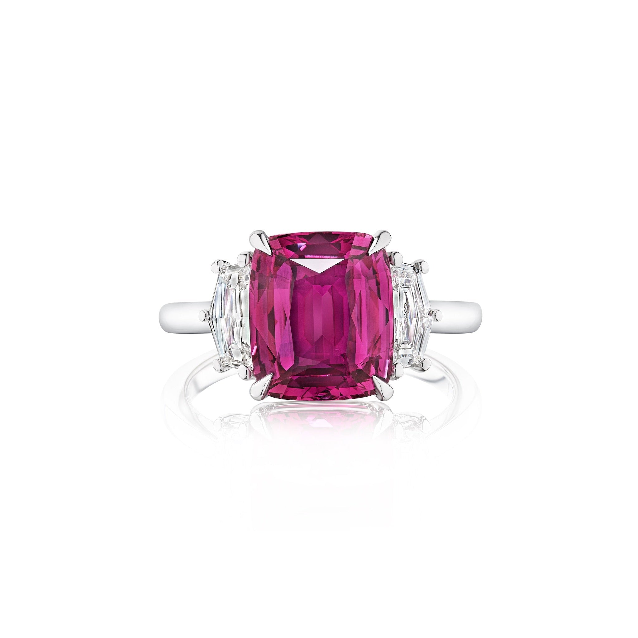 The Pink Sapphire Cushion Cut Engagement Ring in White Gold features a central cushion-cut pink sapphire and Cadillac diamond side stones, shown on a white background.