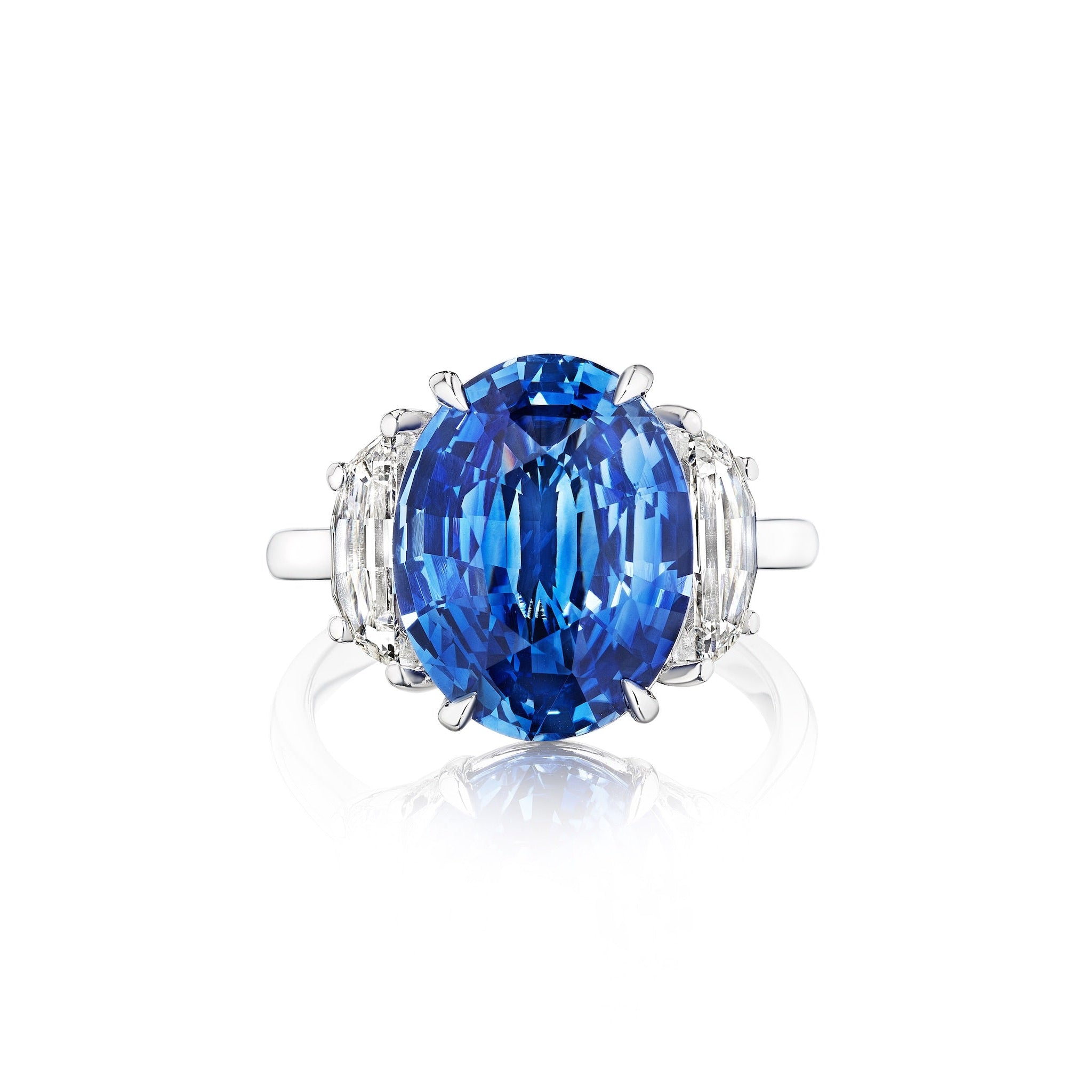 The Modified Oval Blue Sapphire Engagement Ring in Platinum features a central oval blue sapphire accented by sparkling modified half moon side stones.