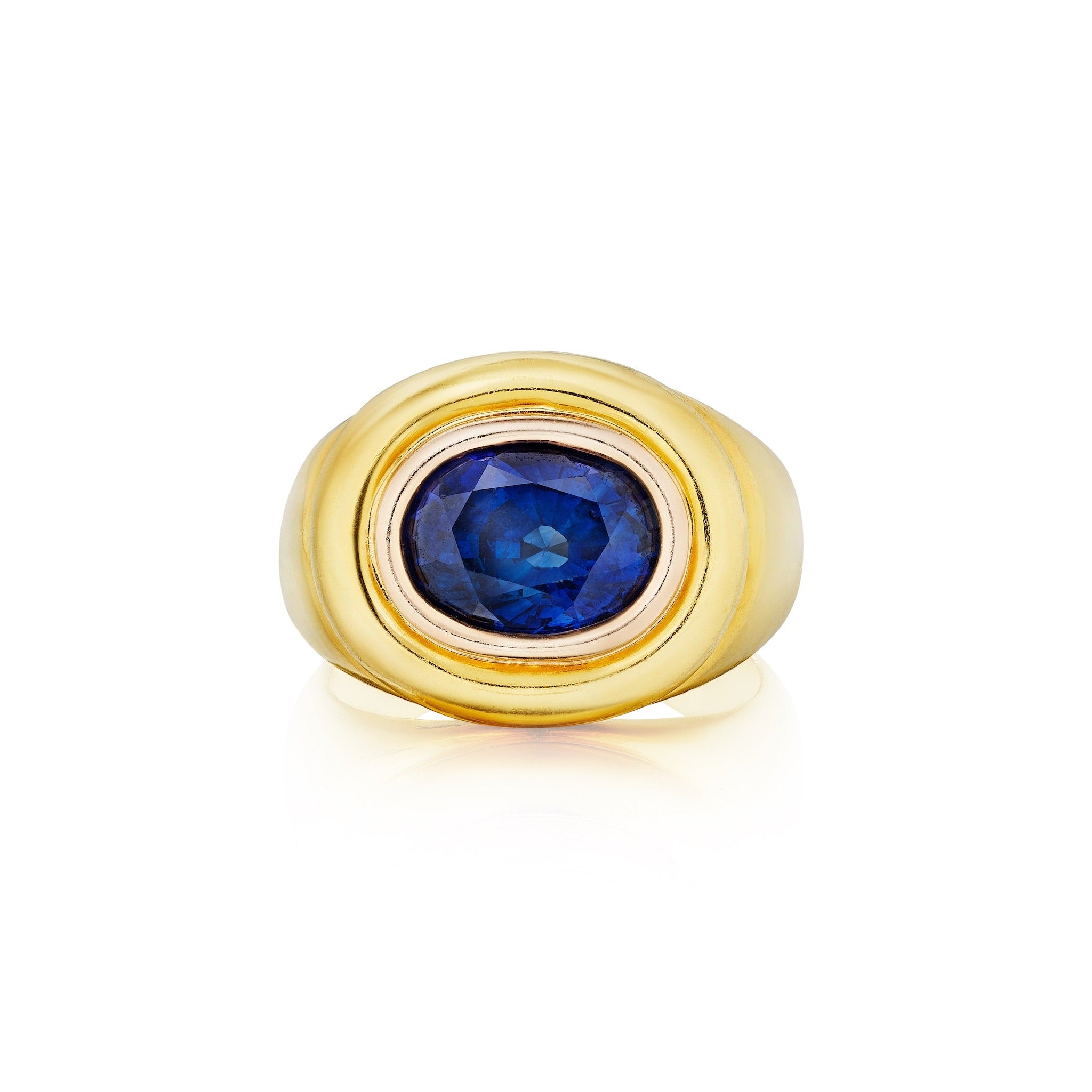 The Gold and Sapphire Ring is a vintage 1970s piece with a round, faceted deep blue sapphire set in gold, elegantly displayed on a white background.
