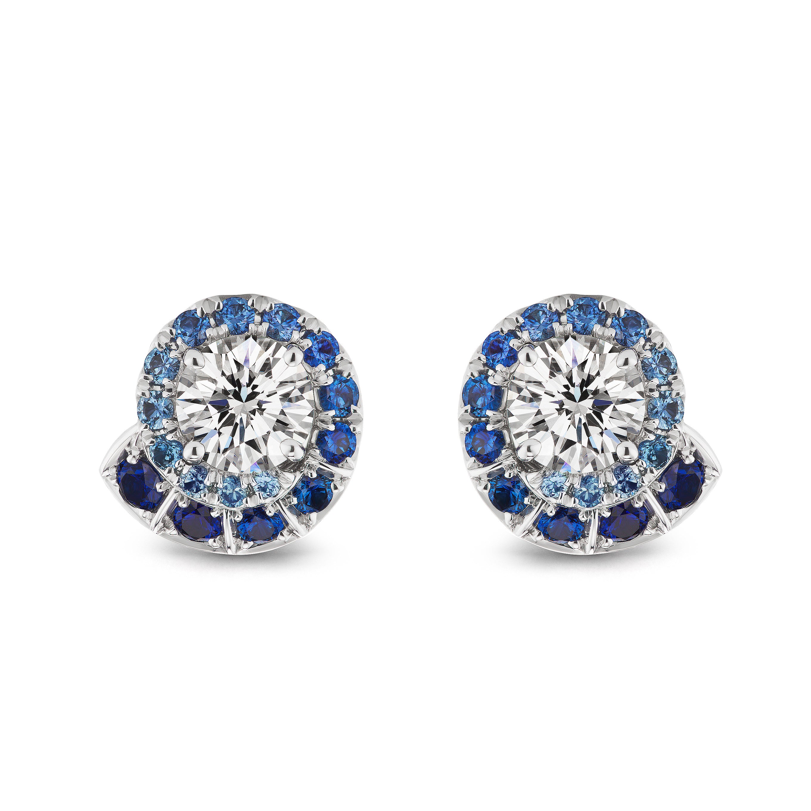 The Ombré Swirl Ear Jackets in white gold feature a central clear gemstone, encircled by a spiral of multicolor sapphires in varying blue shades.