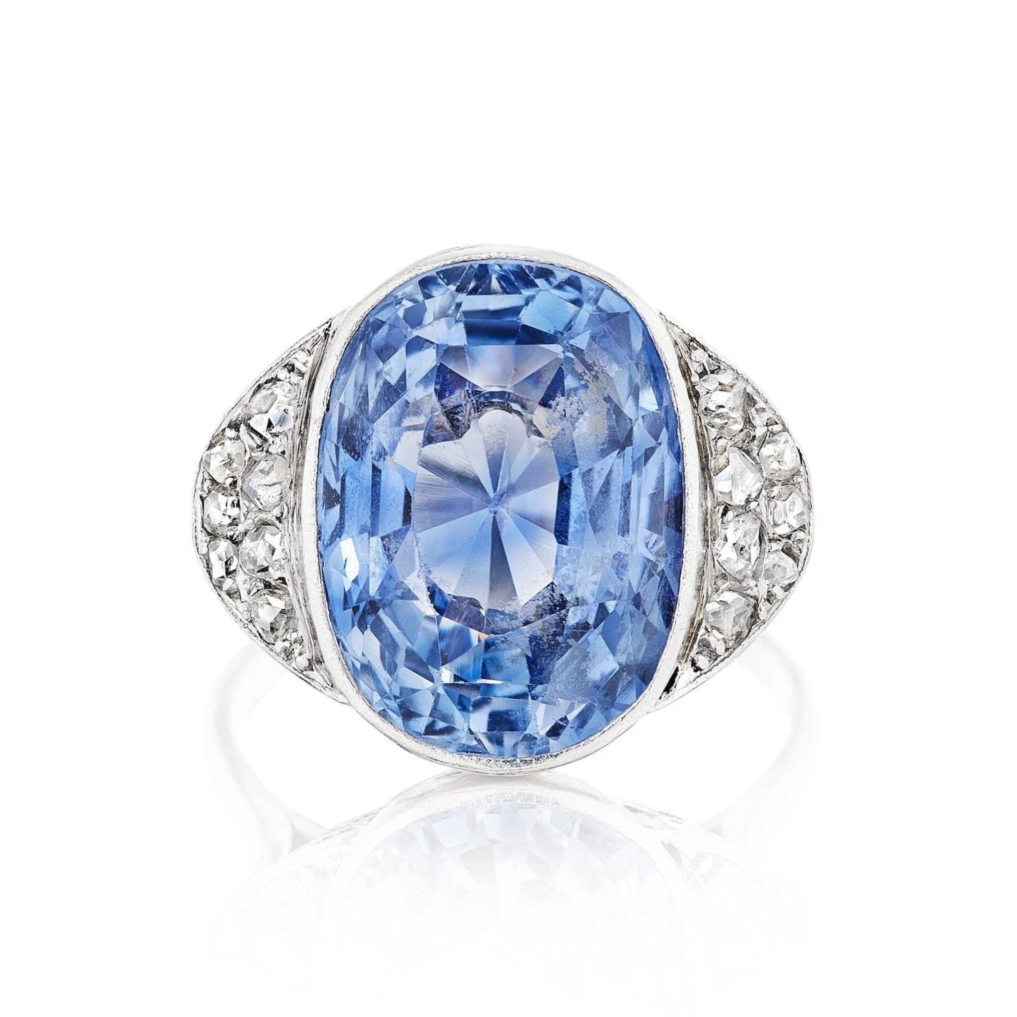 The Sapphire and Diamond Ring showcases a large oval Ceylon sapphire at the center, accented by clusters of rose-cut diamonds on a silver band.