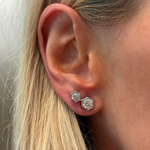 A close-up of a woman's ear adorned with Hexagon Bezel Set Round Diamond Duo Studs in 18k gold. Two duo studs are worn in each lobe, with her blonde hair softly framing her face and partially covering one side.