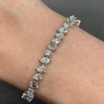 The Mixed Shape Diamond Tennis Bracelet, set with round, baguette, and marquise diamonds, sparkles on a wrist against a dark background.
