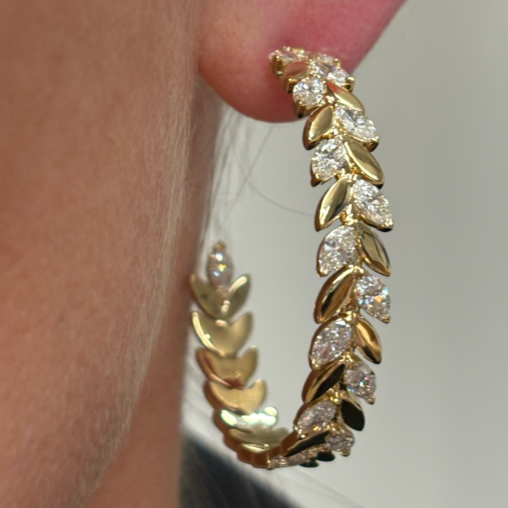 Close-up of the Alternating Marquise Diamond Floral Hoops in Yellow Gold, featuring a laurel leaf-inspired design and sparkling marquise diamonds, worn on an ear.