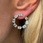 A close-up of a person’s ear with straight blonde hair, wearing Emerald Cut Diamond Front to Back Hoop Earrings in white gold.