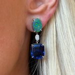 A close-up of a woman’s ear wearing Asscher Cut Sapphire, Emerald, Oval Boulder Opal and Diamond Drop Earrings in White Gold.