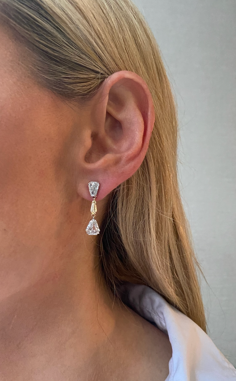 Close-up of a woman's ear wearing the This & That Champagne Flute Drop Earrings, crafted in 18K yellow gold with fancy yellow and white mixed shape diamonds in pear and rectangular cuts.