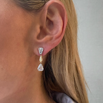 Close-up of a woman's ear wearing the This & That Champagne Flute Drop Earrings, crafted in 18K yellow gold with fancy yellow and white mixed shape diamonds in pear and rectangular cuts.