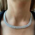 A woman wears the Marquise Floral Tennis Necklace in White Gold, its leaf-inspired design resting elegantly on her neck and collarbone against a blurred background.