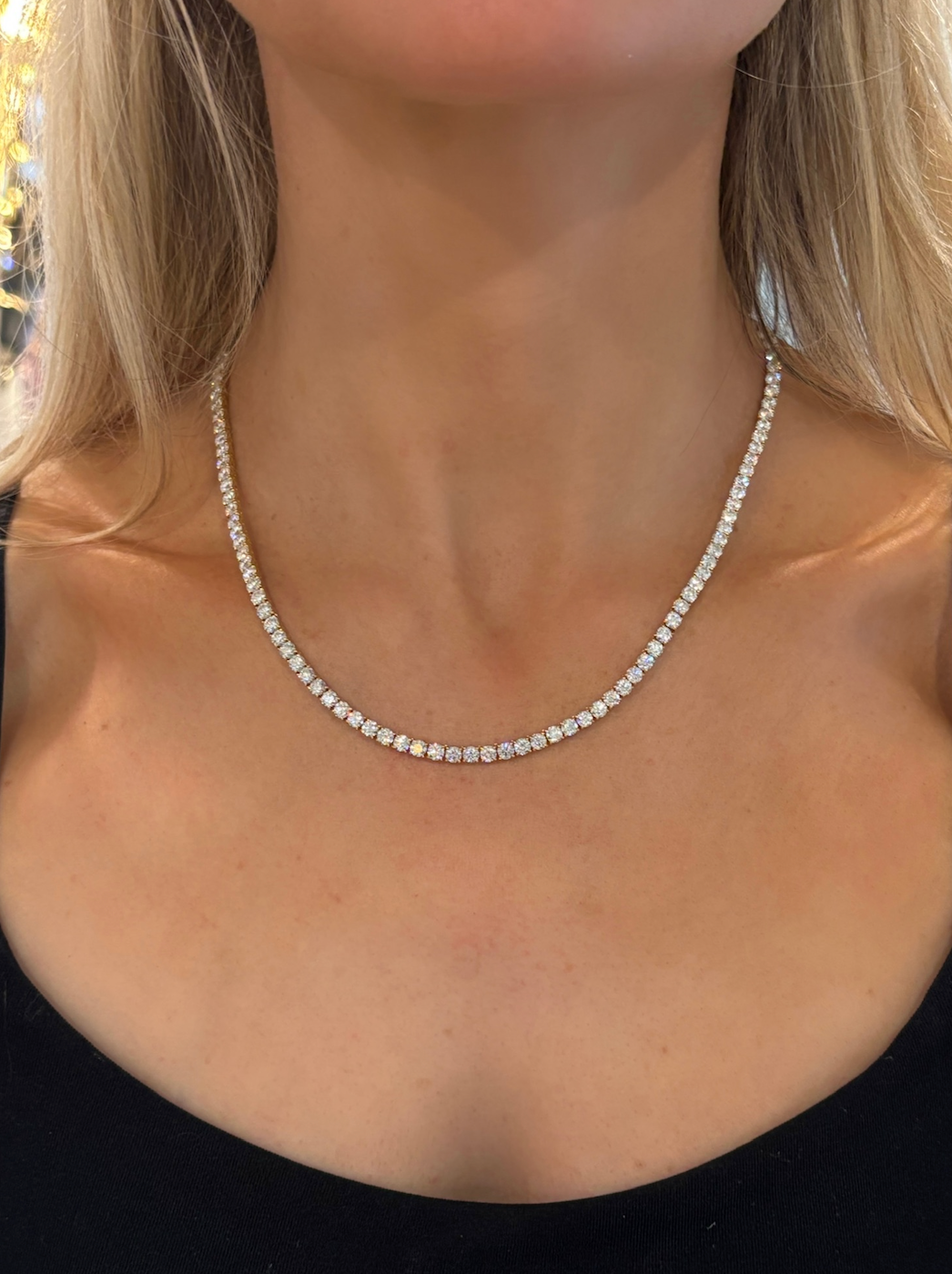 A woman wears the Adjustable Round Brilliant Diamond Tennis Necklace against her bare neck, with a black top visible at the bottom of the image.