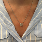 A close-up of a person wearing the Asscher Cut Diamond Mosaic Necklace in white gold, featuring a geometric pendant, shown against a blue and white striped collared shirt.