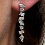 A close-up of an ear wearing Mixed Shape Diamond Drop Earrings with Kite Shape Stones in white gold, featuring a vertical row of sparkling diamonds.