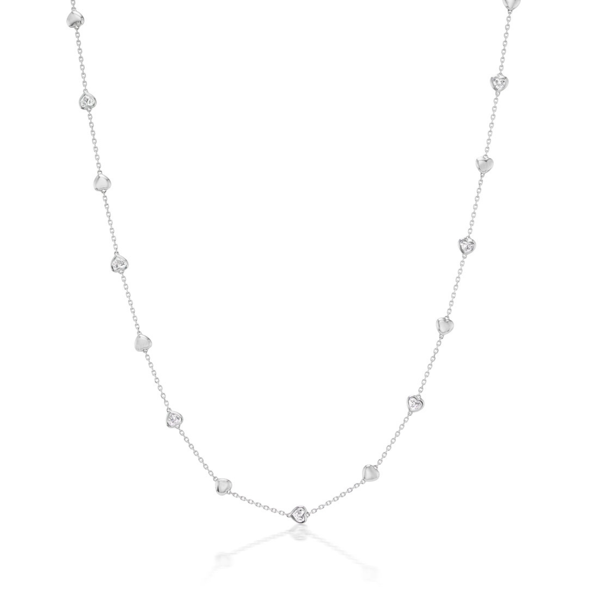 The Serpentine Station Necklace features alternating metal hearts and bezel-set heart diamonds on a fine 17-inch chain, elegantly displayed on a plain white background.