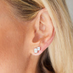 Close-up of a woman's ear with blonde hair tucked back, wearing Duo Studs in White Gold with Emerald Cut Diamonds. These sparkling earrings are made-to-order for a personalized touch.