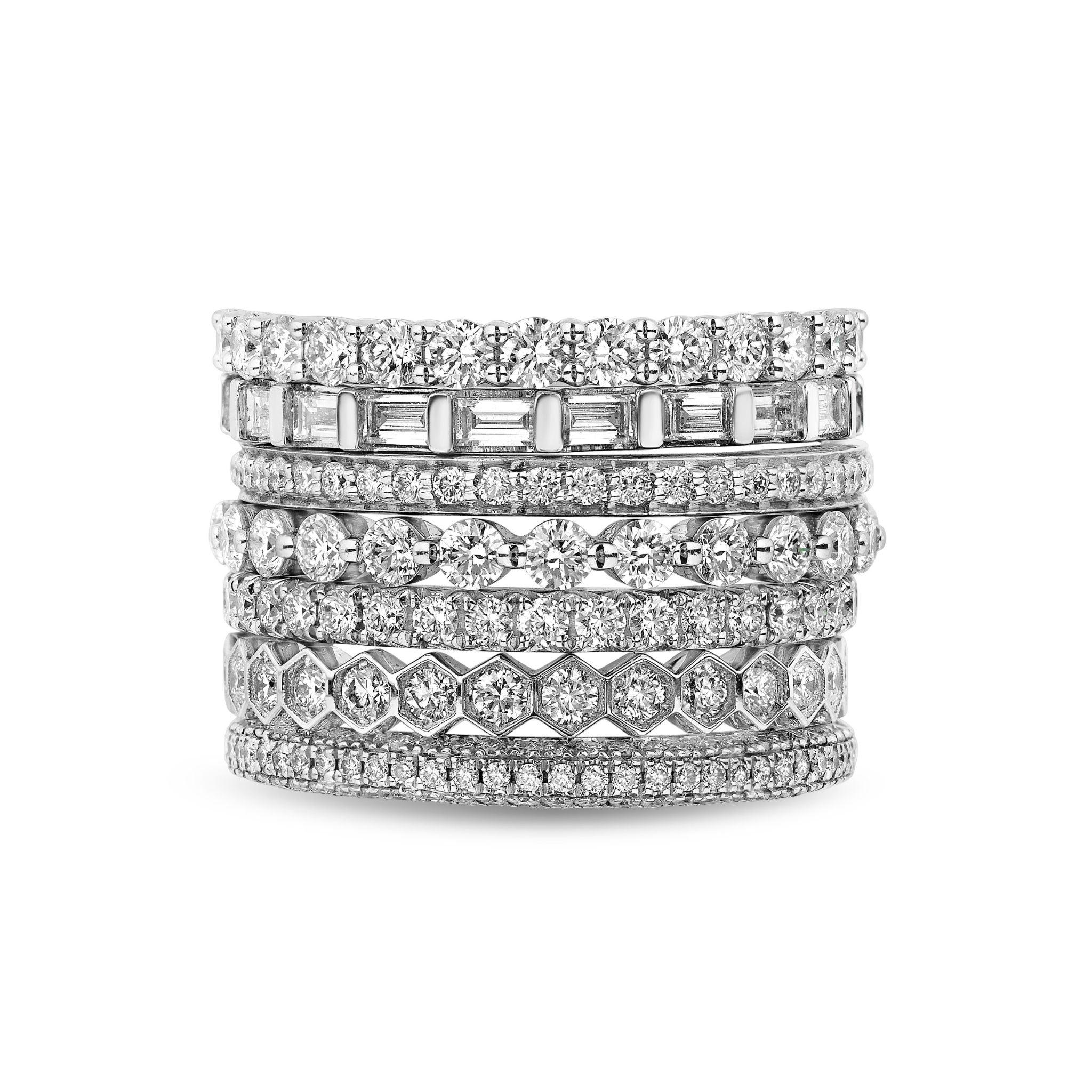 Seven Stackable Diamond Rings, each featuring unique shapes and sparkling white diamonds, are displayed in a neat vertical stack against a white background.
