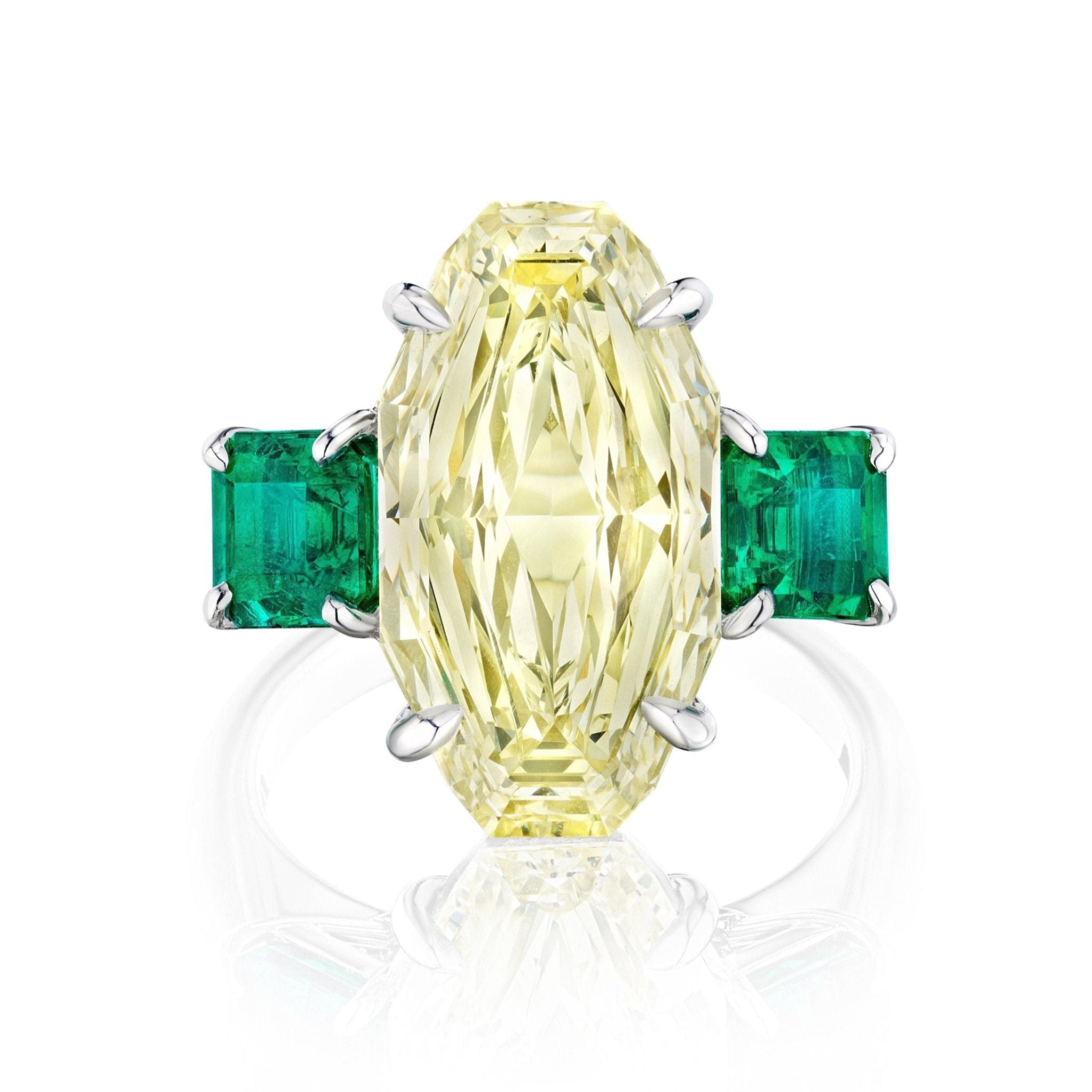 The Step Cut Oval Yellow Diamond Engagement Ring features a central yellow diamond with square emerald side stones, all set in elegant 18K white gold.