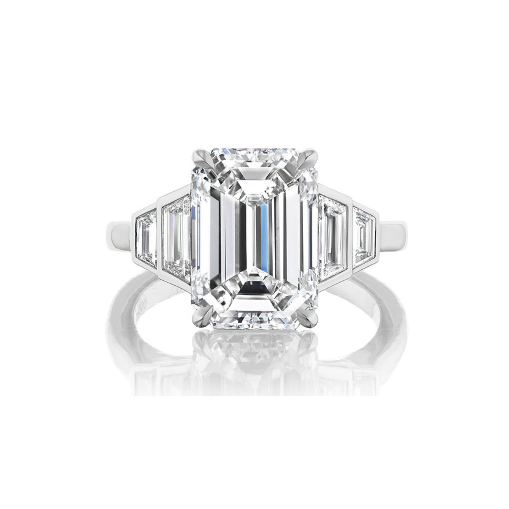 The Echo Emerald Cut Diamond Engagement Ring features a platinum band with a striking emerald-cut center and bezel set graduating trapezoid side stones—an elegant choice for those seeking sophisticated bridal rings.