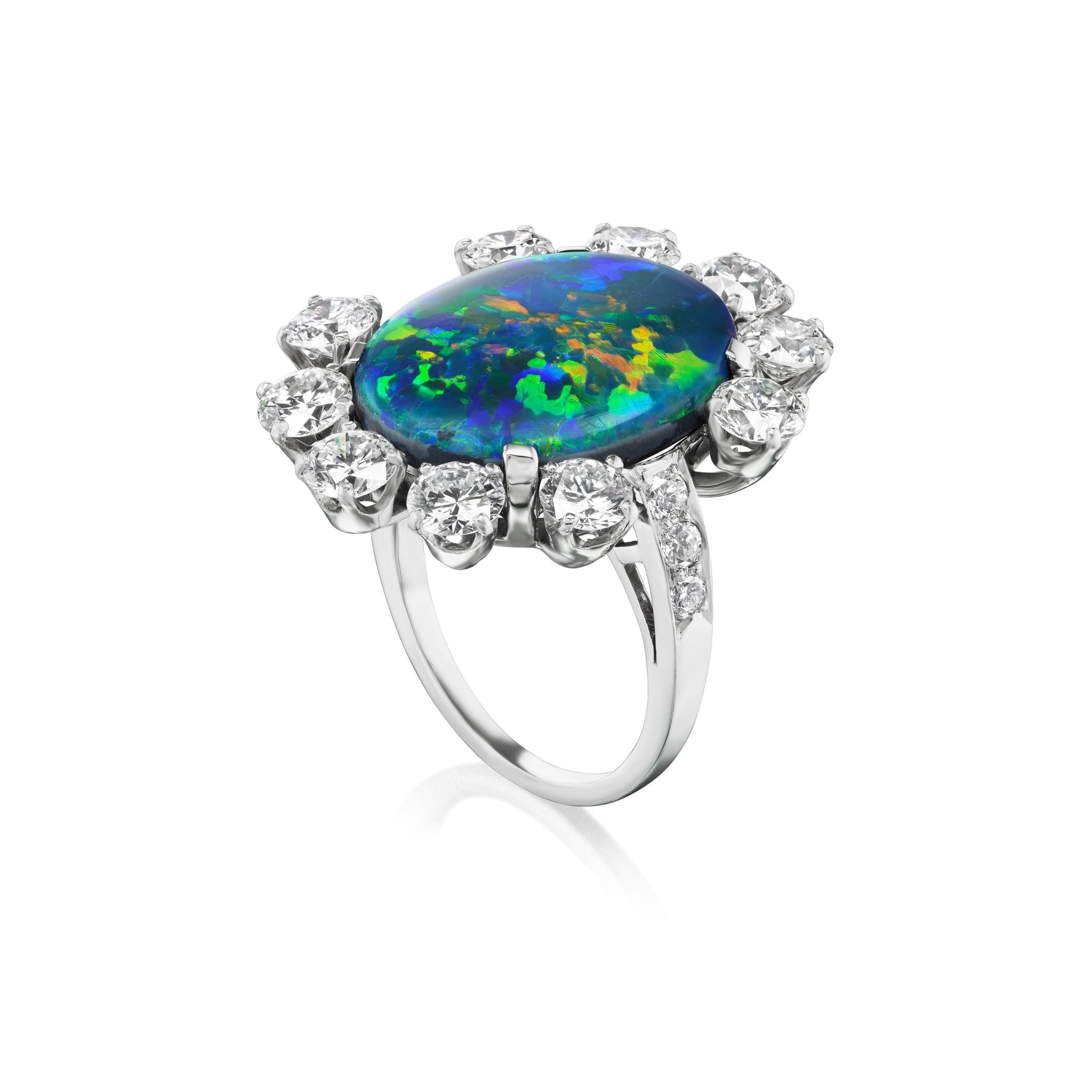 The Sunburst Oval Opal Ring features a large oval opal with blue, green, and yellow hues, encircled by round brilliant diamonds and pavé accents on a sleek band.