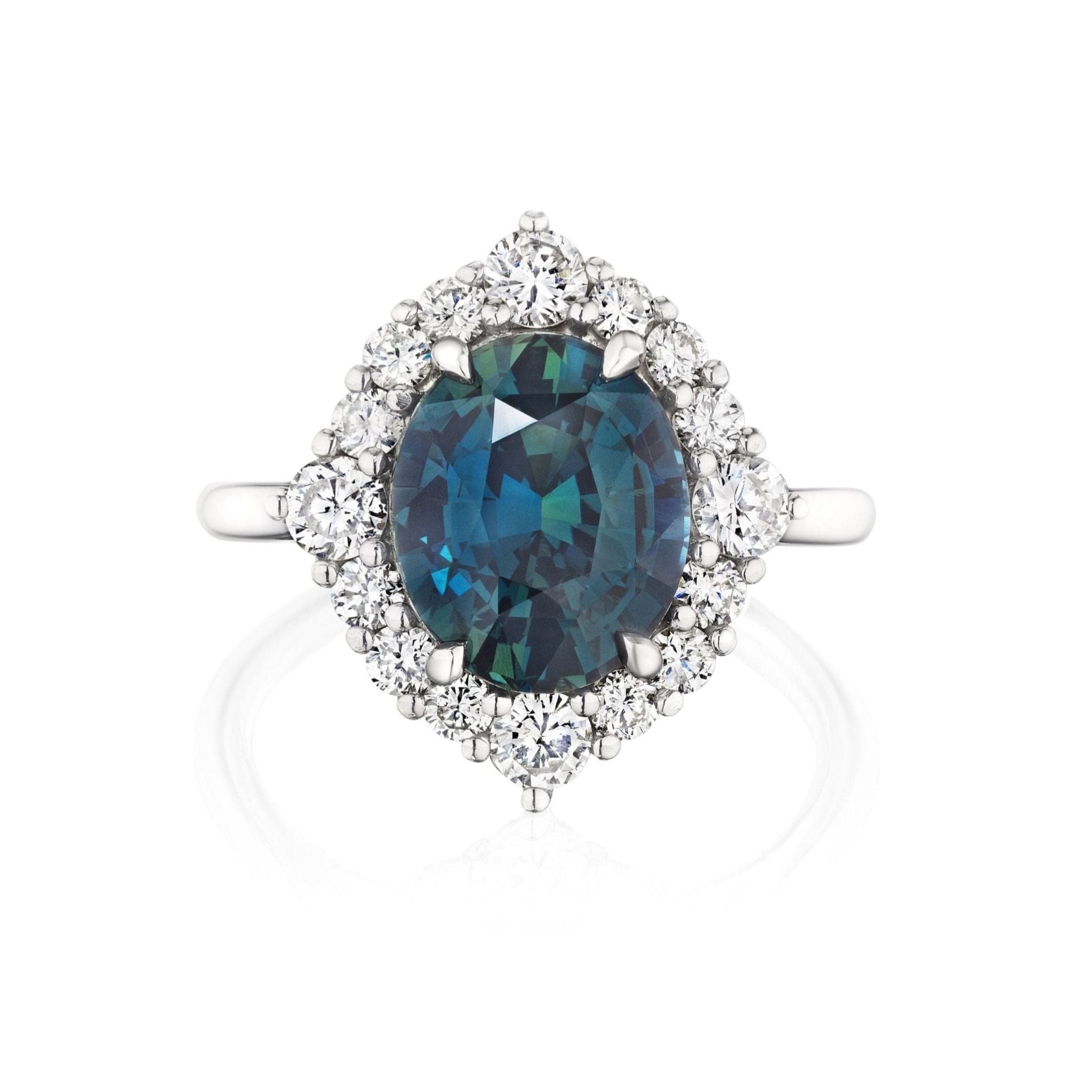 The Teal Oval Sapphire Engagement Ring with Diamond Halo showcases an oval teal sapphire at the center, surrounded by a halo of round white diamonds, displayed on a white background.
