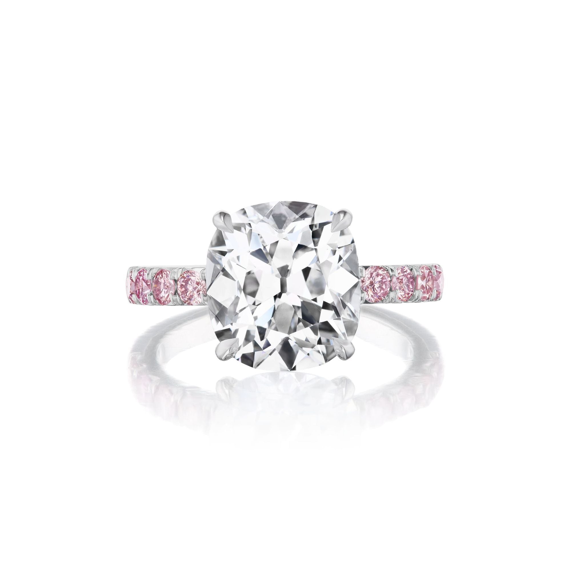 The Cushion Cut Diamond Engagement Ring with Pink Sapphire Pavé Band features a large cushion-cut diamond on a platinum band adorned with pink sapphires, set against a plain white background.