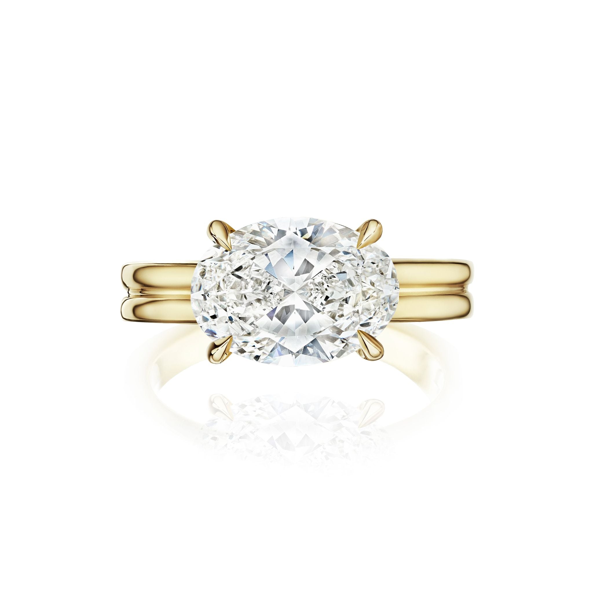 The East-West Oval Diamond Double Band Engagement Ring in Yellow Gold features a striking oval-cut diamond solitaire set in prongs, showcased against a white background.