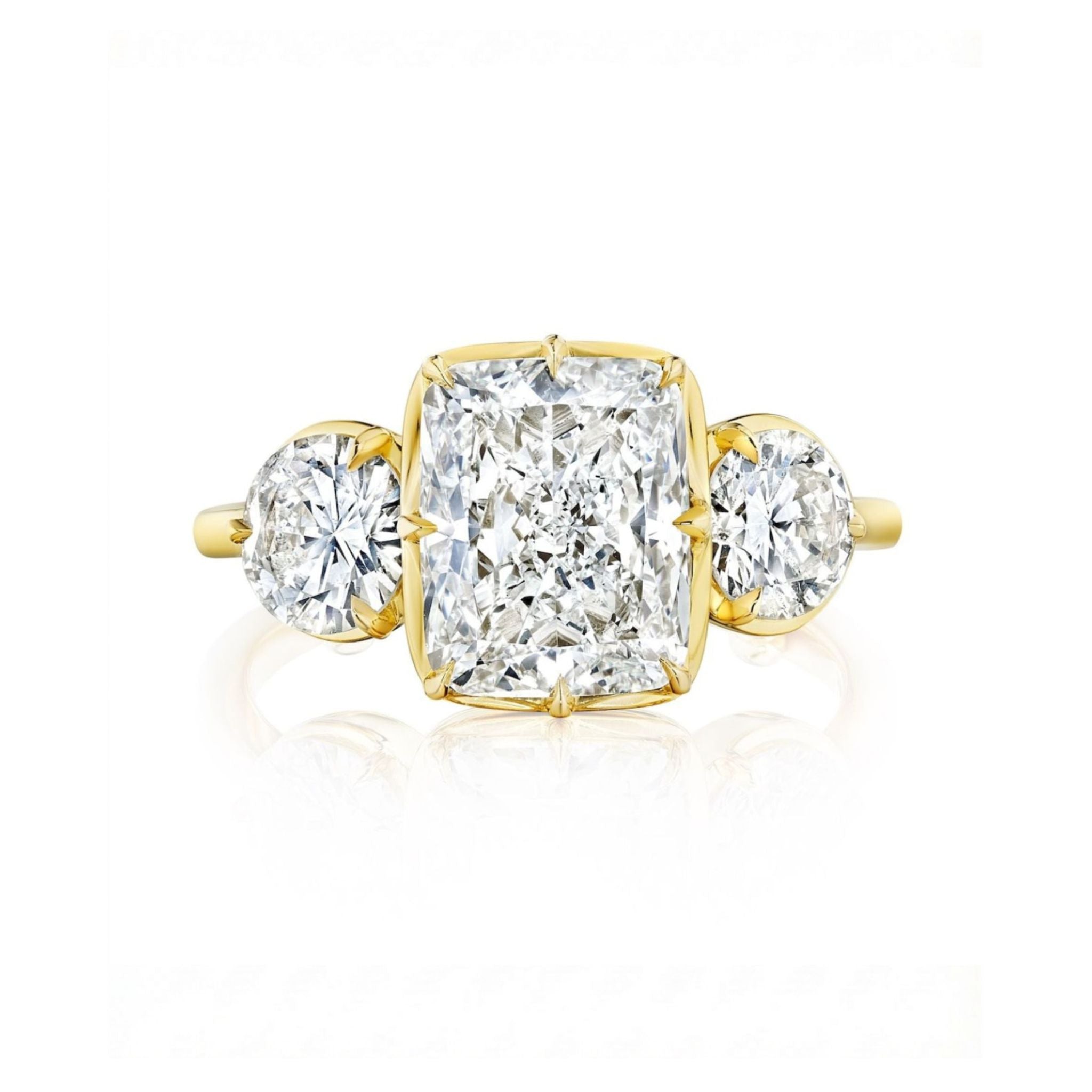 The Collet Set Cushion Cut Diamond Engagement Ring features a large cushion cut diamond with round side stones, all set in an 18k yellow gold band against a white background.