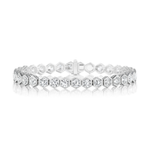 The Large Hexagon Bezel Set Diamond Tennis Bracelet, crafted in silver with hexagonal links—each adorned with round brilliant diamonds—rests elegantly on a white reflective surface.