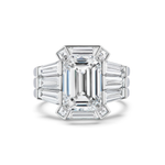A platinum ring with a striking, emerald-cut center diamond framed by baguette and trapezoid diamonds in an Art Deco-inspired geometric arrangement—beautifully enhanced by the Geometric Bezel Set Baguette and Asscher Cut Diamond Ring Jacket in white gold for extra elegance.