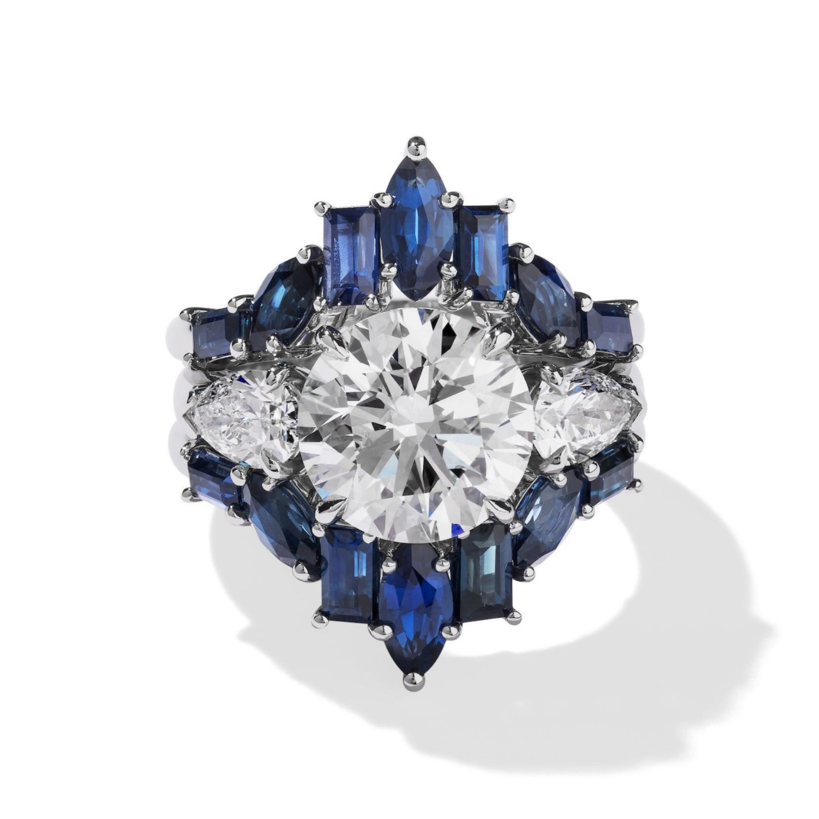 The Baguette and Marquise Sapphire Engagement Ring Jacket in White Gold showcases a striking round center diamond, encircled by marquise, pear, and baguette-cut sapphires and accented with smaller diamonds.
