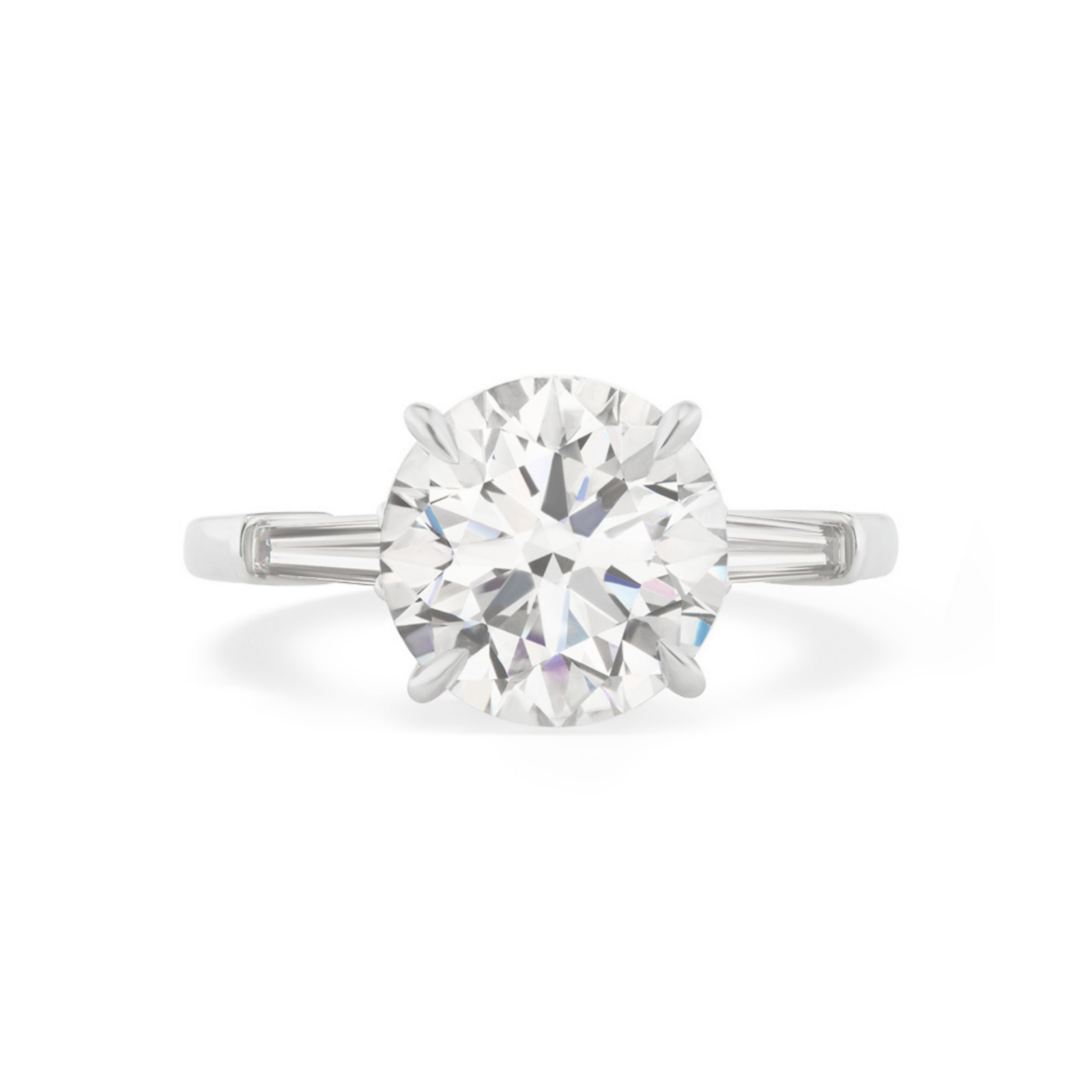 The Round Brilliant Diamond Engagement Ring with Tapered Baguette Side Stones features a simple white gold or platinum band, highlighting a large round-cut center diamond flanked by two tapered baguette diamonds on each side.
