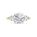 A round brilliant diamond engagement ring featuring a stunning three-stone design, showcasing a large round center diamond accented by two heart-shaped side stones.