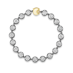 The Collet Set Round Diamond Tennis Bracelet in Black Rhodium showcases brilliant round diamonds set in silver bezels with a hint of black rhodium, elegantly finished with an 18k yellow gold clasp and displayed on a white background.
