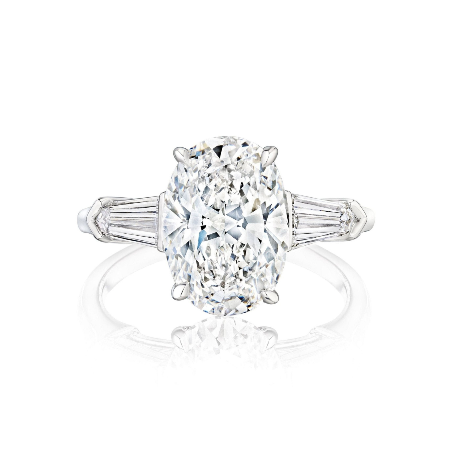 The Oval Shape Diamond Engagement Ring with Bullet Side Stones features an oval-cut diamond flanked by tapered baguette side stones, all set on a slender, polished platinum band and displayed against a white background.