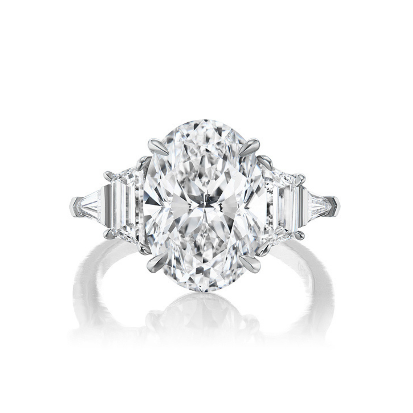 The Oval Diamond Engagement Ring with Trapezoid and Tapered Baguette Side Stones features an elegant oval center diamond flanked by sparkling trapezoid and tapered baguette stones, all set in a polished metal band—an eye-catching addition to any bridal ring collection.