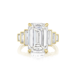 The Triple Echo Emerald Cut Diamond Engagement Ring with Bezel Set Baguette Side Stones features an 18k gold band showcasing a striking emerald-cut diamond center stone, accented by bezel-set baguette side stones on each side for a refined and symmetrical look.