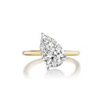 The Diagonally Set Pear Shape Diamond Engagement Ring features a large pear-shaped diamond solitaire, crafted in 18K yellow gold and displayed against a white background.