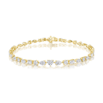 An elegant 18k gold tennis bracelet featuring a heart-shaped center with mixed shape prong set diamonds—beautifully displayed against a white background.