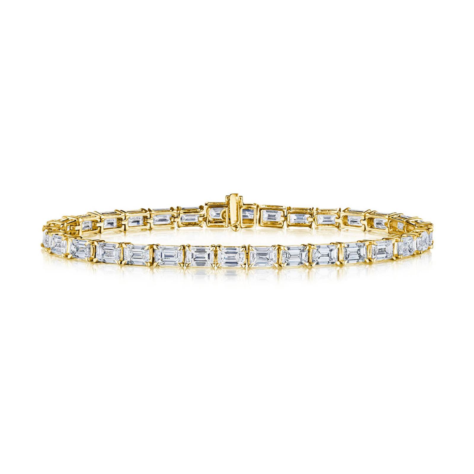 Introducing the East-West Emerald Cut Tennis Bracelet: a stunning 18K gold bracelet showcasing a continuous row of emerald cut diamonds set in prongs, secured by a central clasp. Elegantly presented against a white background.