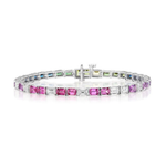 The Multicolor Emerald Cut Sapphire Tennis Bracelet showcases alternating rectangular gemstones in vibrant shades of pink, purple, blue, green, and clear, expertly set in 18K white gold and elegantly displayed on a white background.