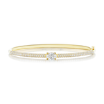 The East-West Set Oval Shape Diamond Pavé Bangle features an elegant 18k gold design with a central oval-shaped diamond and two rows of pavé diamonds along the band, displayed on a white background.
