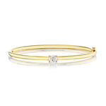 An elegant East-West Oval Solitaire Diamond Bangle crafted from a slender 18K yellow gold band, showcasing a central east-west set oval solitaire diamond and accented with a smaller diamond at one end, presented against a white background.