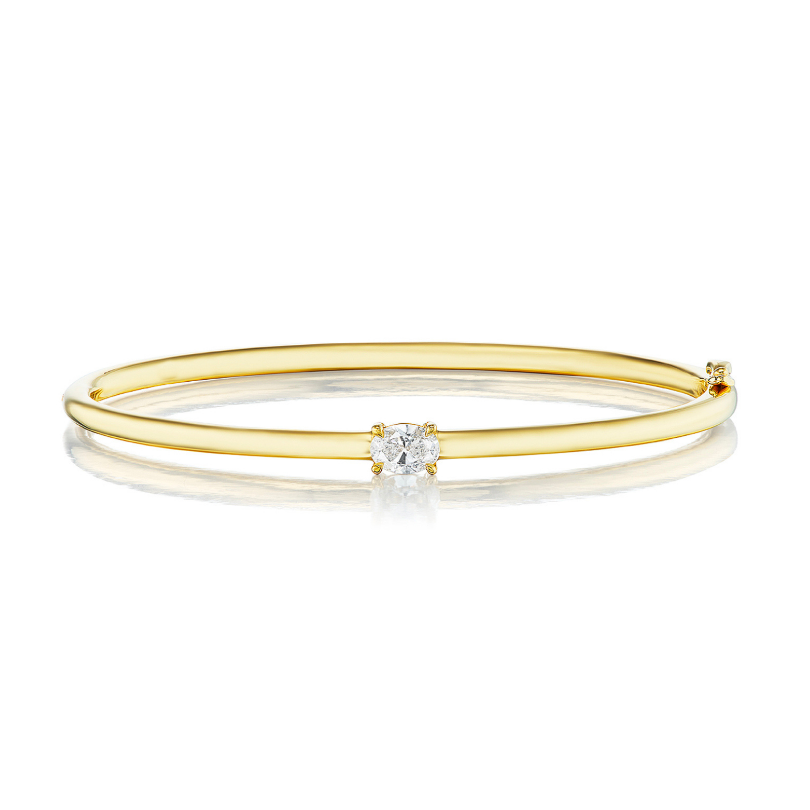 An elegant East-West Oval Solitaire Diamond Bangle crafted from a slender 18K yellow gold band, showcasing a central east-west set oval solitaire diamond and accented with a smaller diamond at one end, presented against a white background.