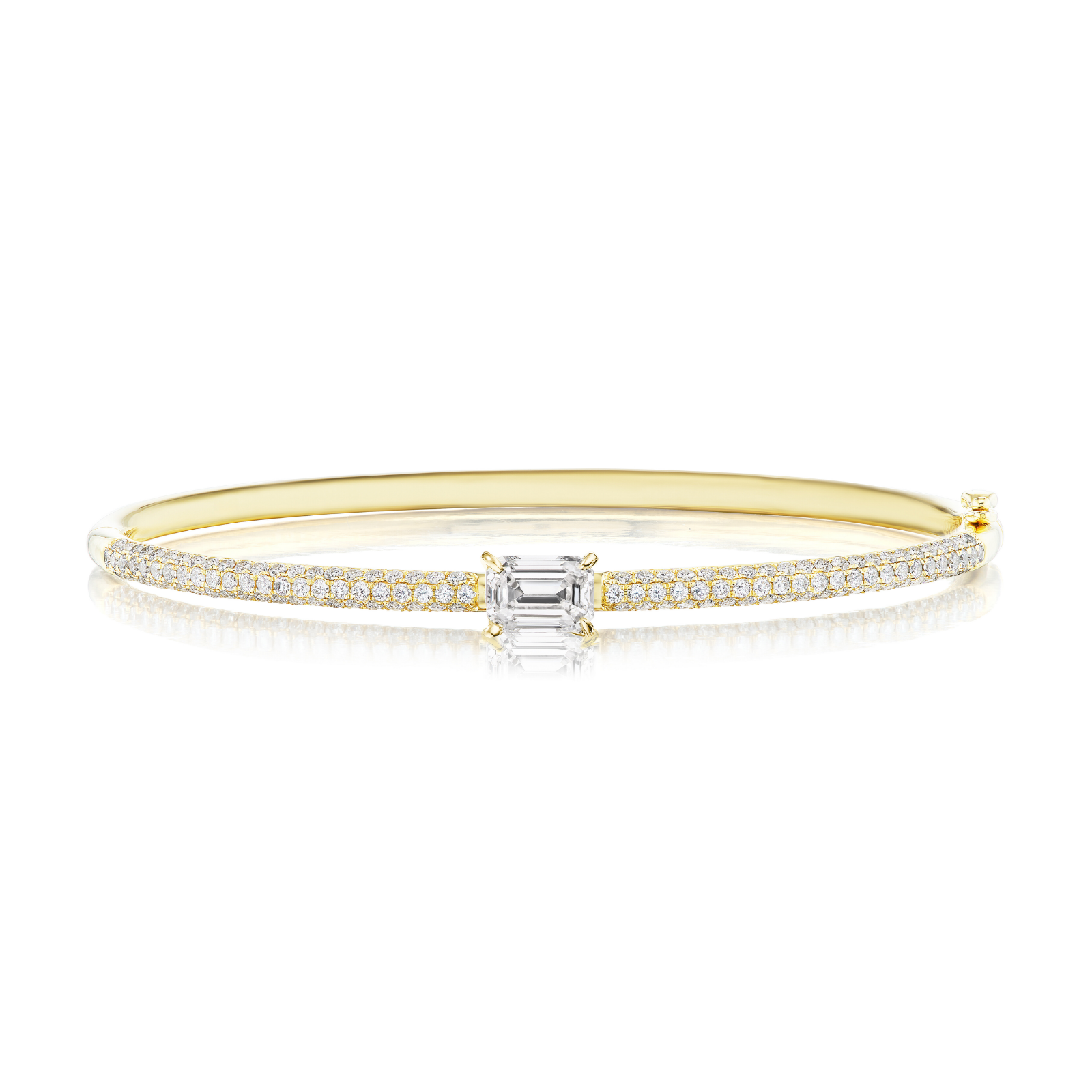 The East-West Set Emerald Cut Diamond Pavé Bangle is a stunning 18k gold bangle bracelet featuring a central emerald-cut diamond and two rows of small round diamonds along the band, displayed on a white background.