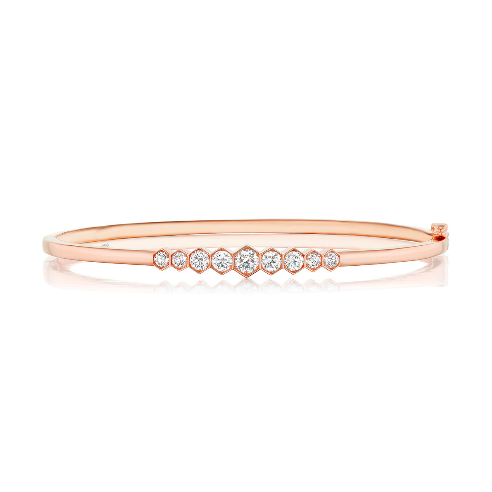 The Graduated Hexagon Bezel Set Diamond Bangle showcases a slim silhouette in elegant 18k rose gold, with a polished and reflective surface. Along the top center, a row of round white diamonds is artfully set in graduated hexagon bezels for a timeless and sophisticated look.