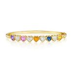 The Chroma Heart Beats Bezel Set Heart Shape Sapphire and Diamond Bangle in Yellow Gold features heart-shaped sapphires and diamonds in a vibrant array of colors—purple, pink, yellow, clear, blue, and orange. Each gem is artfully bezel set in radiant 18k yellow gold and arranged in a row along the front of the bangle, with their vivid hues beautifully reflected below.